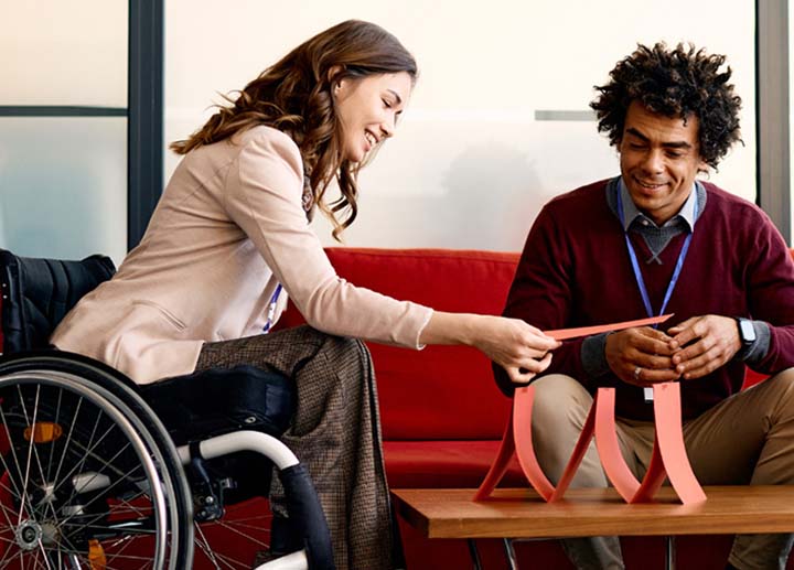 Woman in wheel chair working on diorama with someone else 